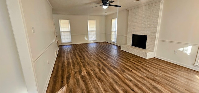 unfurnished living room with ornamental molding, dark wood-type flooring, ceiling fan, and a fireplace