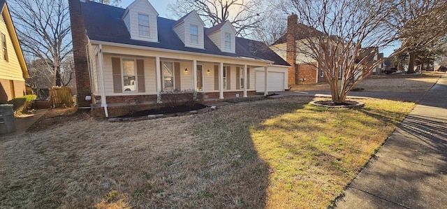 new england style home with a garage, a porch, and a front yard