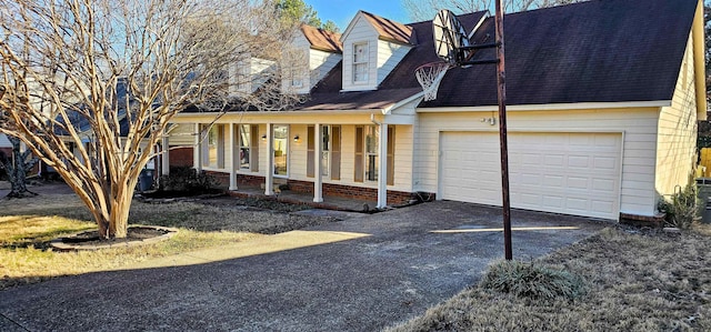 cape cod home featuring a garage and covered porch