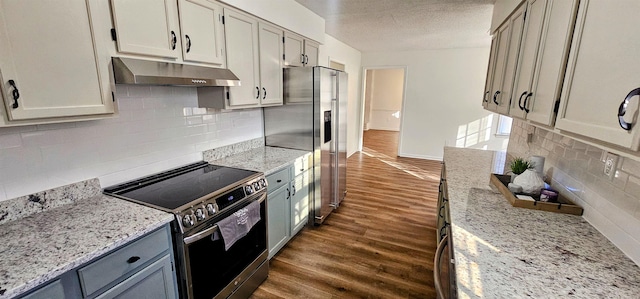 kitchen with stainless steel appliances, light stone countertops, dark hardwood / wood-style floors, and a textured ceiling