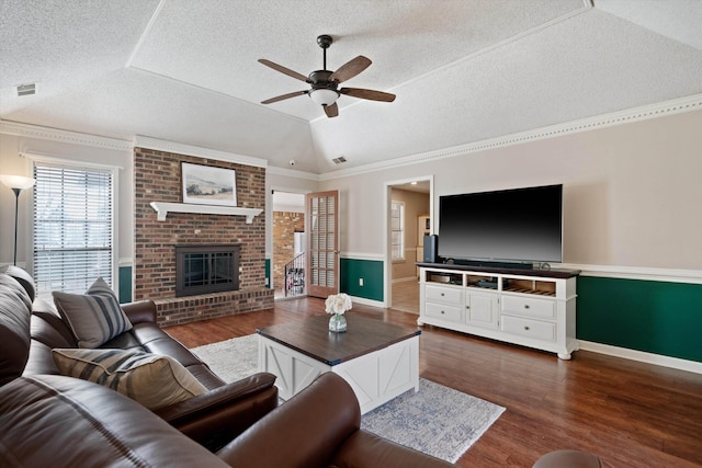 living room featuring lofted ceiling, dark hardwood / wood-style floors, a brick fireplace, and a textured ceiling