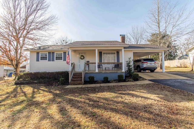 ranch-style house featuring a carport, covered porch, and a front yard