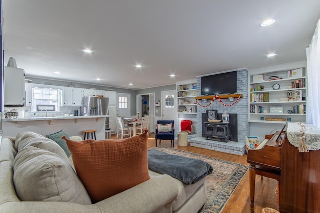 living room featuring wood-type flooring, sink, and a wood stove