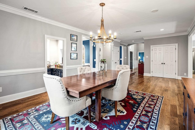 dining space featuring crown molding, dark wood-type flooring, and an inviting chandelier