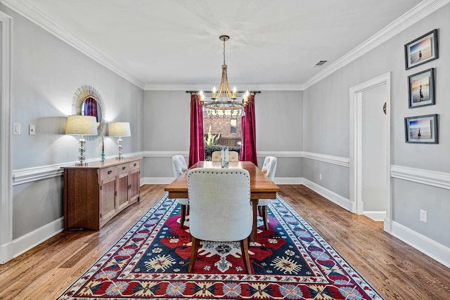 dining space featuring ornamental molding, a chandelier, and light wood-type flooring