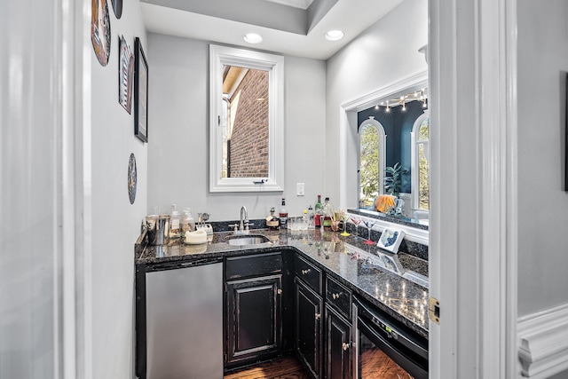 bar featuring dark stone counters, stainless steel fridge, and sink