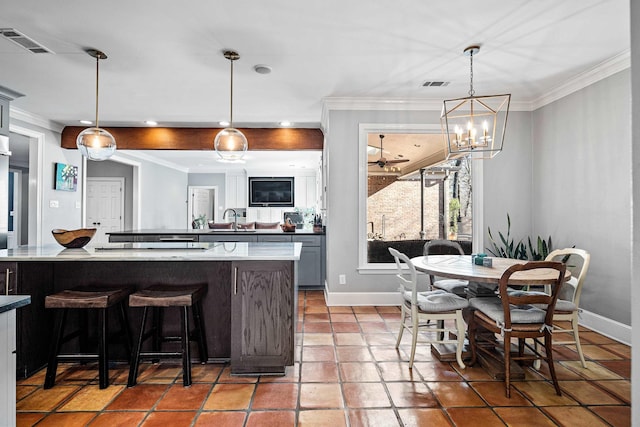 kitchen featuring sink, crown molding, gray cabinets, hanging light fixtures, and a kitchen breakfast bar