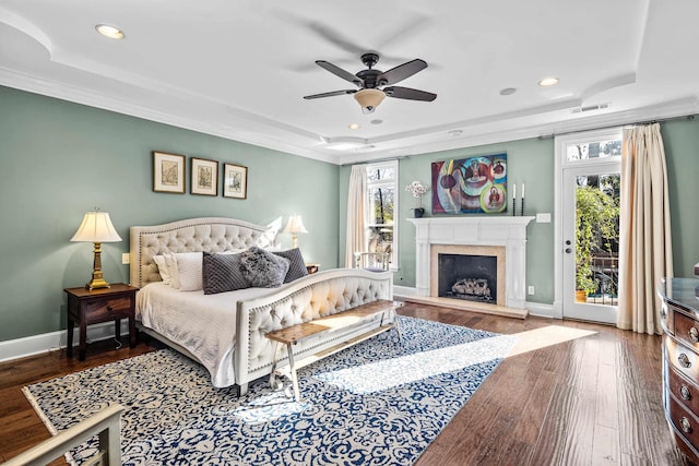 bedroom featuring a raised ceiling, hardwood / wood-style floors, access to outside, and multiple windows