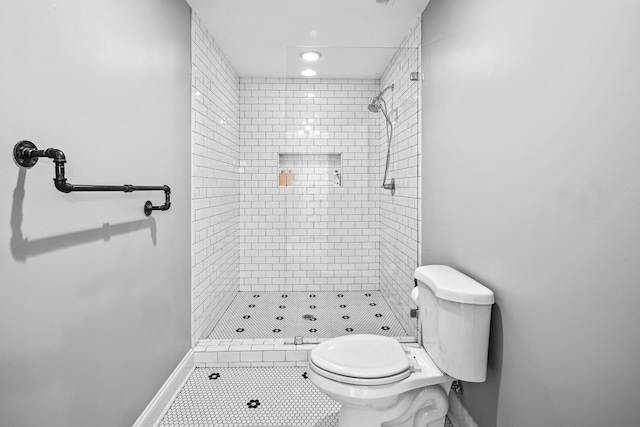 bathroom featuring tile patterned floors, toilet, and a tile shower