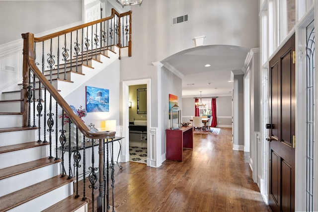 foyer featuring dark hardwood / wood-style flooring, a towering ceiling, and crown molding