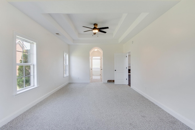 carpeted spare room with a raised ceiling and ceiling fan