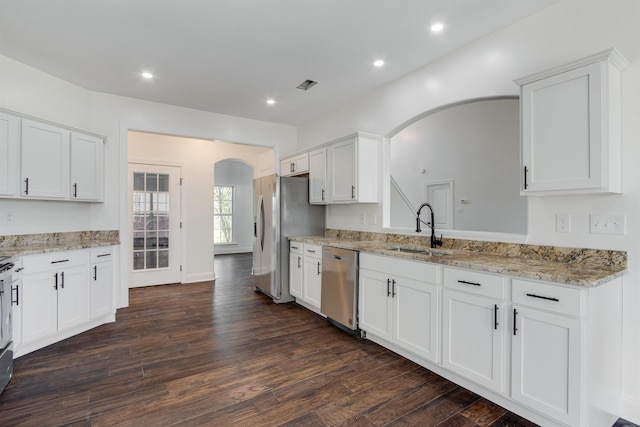 kitchen with appliances with stainless steel finishes, dark hardwood / wood-style floors, sink, white cabinets, and light stone countertops