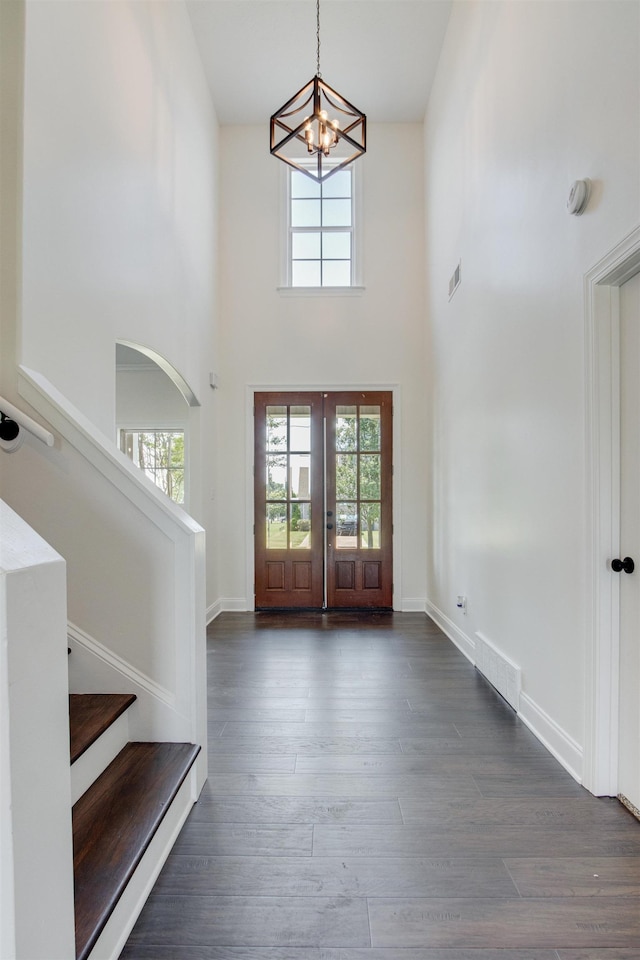 foyer entrance featuring a high ceiling, dark hardwood / wood-style floors, a chandelier, and french doors