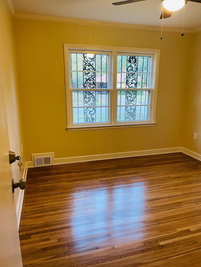 empty room with dark wood-type flooring, ceiling fan, and ornamental molding