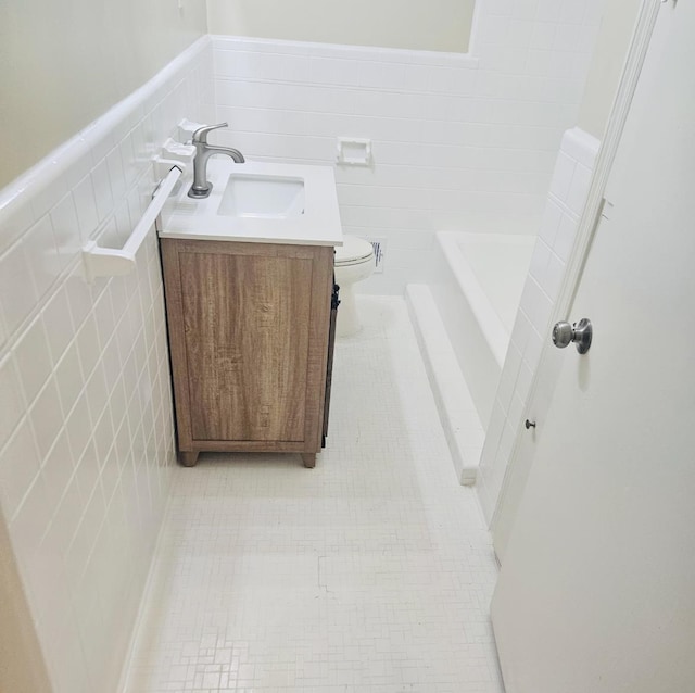 bathroom featuring tile patterned flooring, vanity, tile walls, and toilet