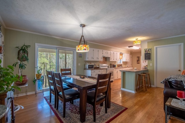 dining area featuring crown molding, a textured ceiling, and light wood-type flooring