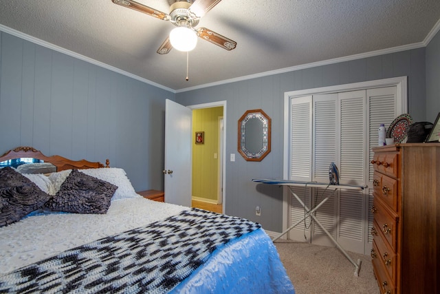 carpeted bedroom featuring a textured ceiling, ornamental molding, a closet, and ceiling fan