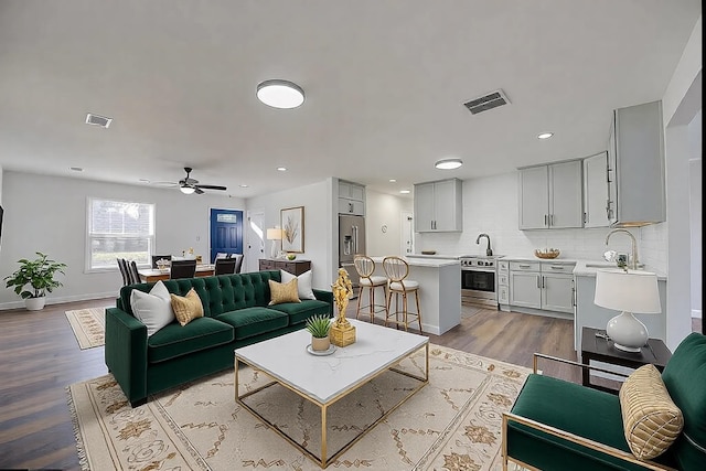 living room featuring sink, ceiling fan, and light wood-type flooring