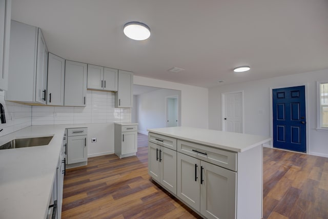 kitchen featuring tasteful backsplash, dark hardwood / wood-style flooring, a center island, and sink