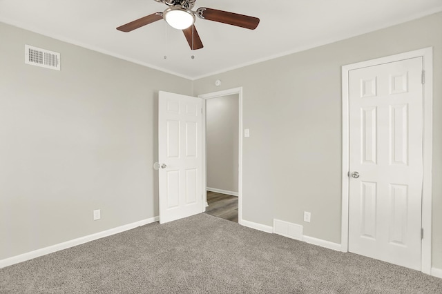 unfurnished bedroom with crown molding, ceiling fan, and dark carpet