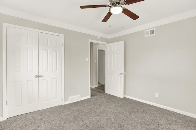 unfurnished bedroom featuring crown molding, ceiling fan, dark carpet, and a closet