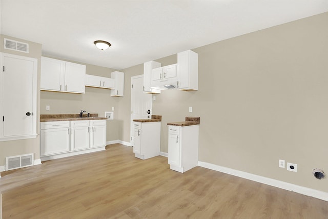 kitchen with white cabinetry, sink, and light hardwood / wood-style floors