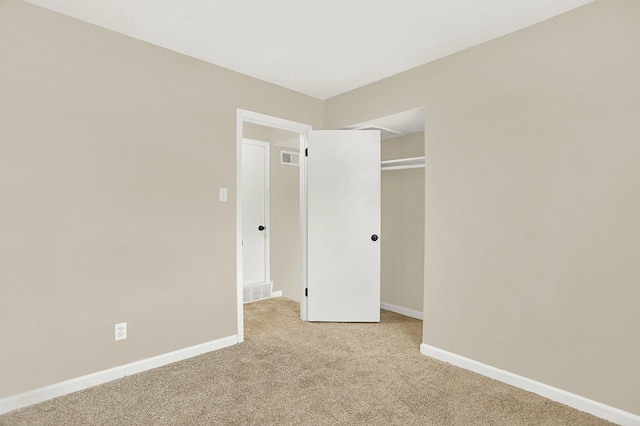 unfurnished bedroom with light colored carpet and a closet