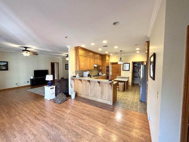 kitchen with light wood-type flooring, stainless steel fridge, a kitchen bar, and kitchen peninsula