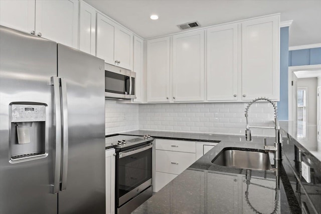 kitchen with dark stone countertops, appliances with stainless steel finishes, sink, and white cabinets