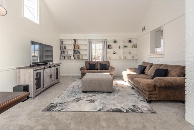 living room with built in shelves, high vaulted ceiling, and light carpet