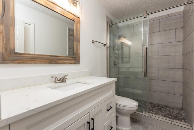 bathroom featuring vanity, a shower with shower door, a textured ceiling, and toilet