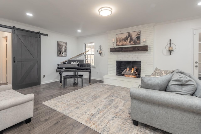 living room featuring dark hardwood / wood-style flooring, crown molding, a fireplace, and a barn door