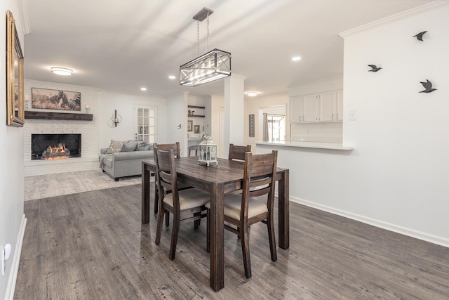 dining room with ornamental molding, dark hardwood / wood-style floors, and a brick fireplace