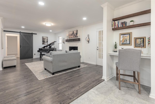 living room with a fireplace, ornamental molding, a barn door, and wood-type flooring