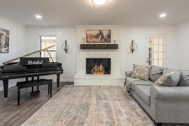 living room with hardwood / wood-style floors, crown molding, and a brick fireplace