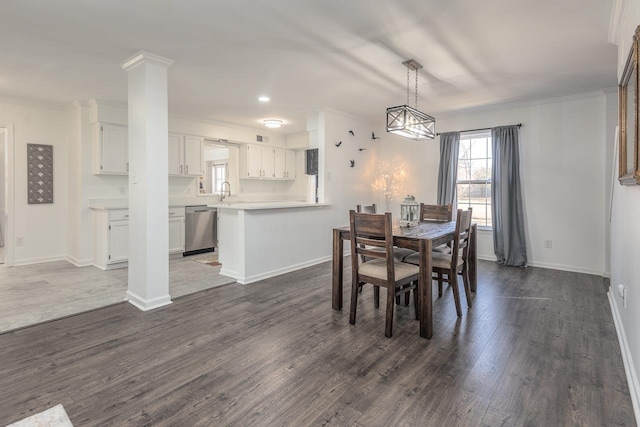 dining room with decorative columns, ornamental molding, dark hardwood / wood-style floors, and sink