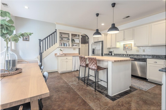 kitchen featuring pendant lighting, butcher block counters, decorative backsplash, a center island, and stainless steel appliances