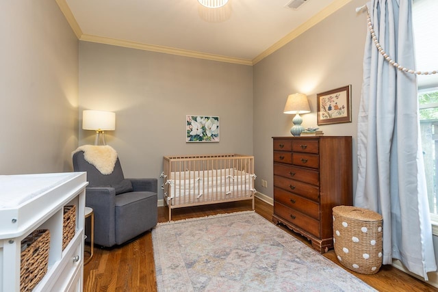 bedroom featuring a crib, crown molding, and dark hardwood / wood-style floors