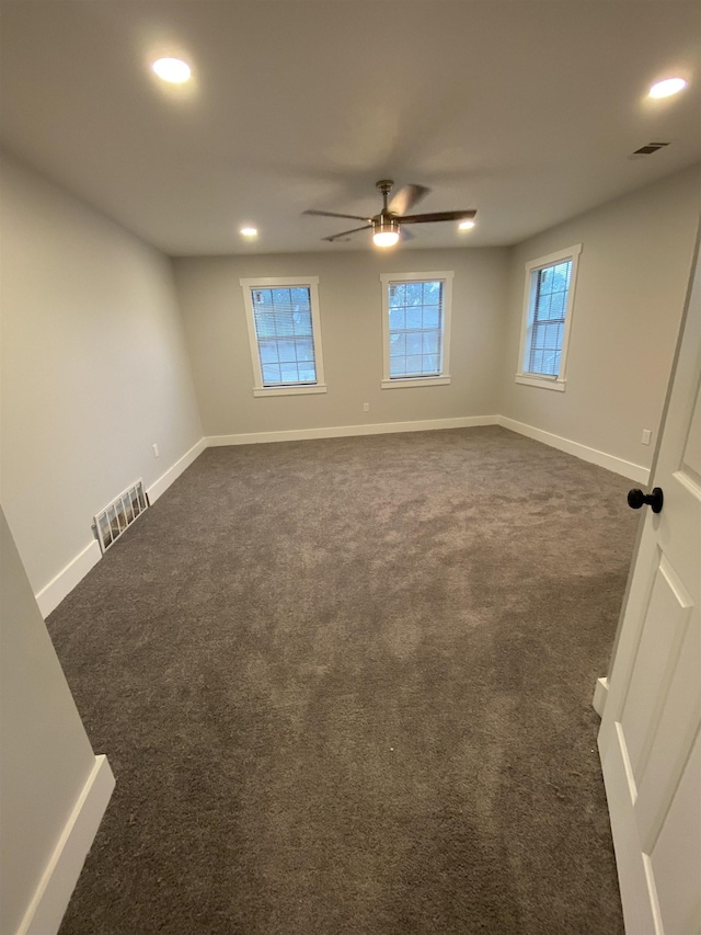 unfurnished room with ceiling fan and dark colored carpet