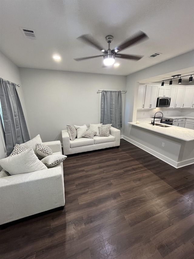 living room featuring sink, dark wood-type flooring, and ceiling fan