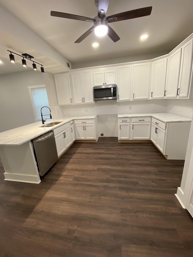 kitchen featuring white cabinetry, sink, kitchen peninsula, stainless steel appliances, and dark wood-type flooring