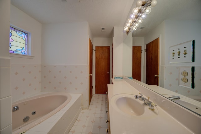 bathroom with vanity, tile walls, tiled bath, and a textured ceiling