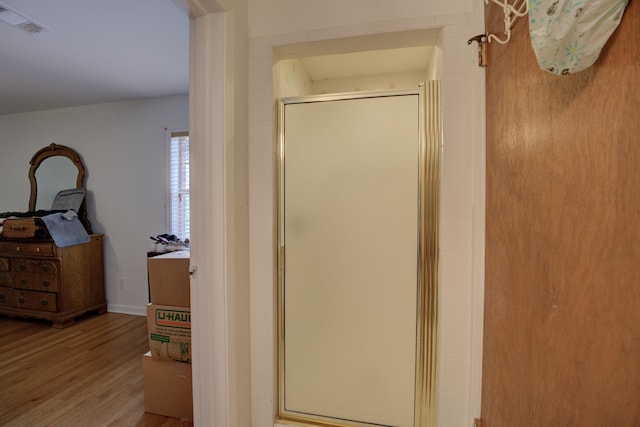 bathroom with hardwood / wood-style flooring and a shower with door