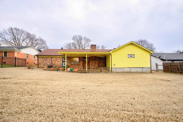 rear view of house featuring a chimney and fence
