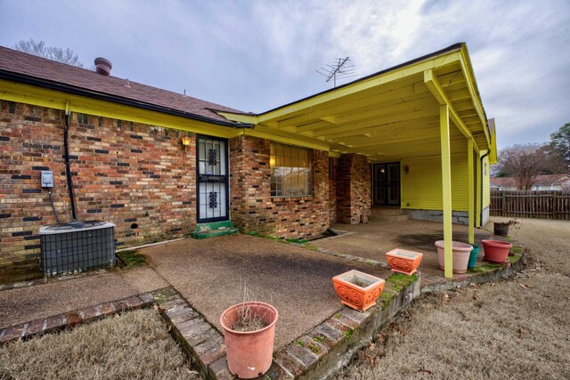 back of house with central air condition unit, fence, brick siding, and a patio