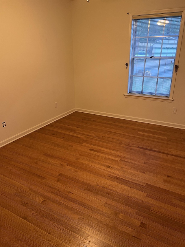 unfurnished room with baseboards and dark wood finished floors