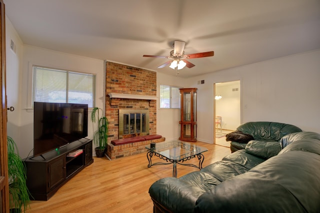 living room with ceiling fan, a fireplace, and light hardwood / wood-style floors