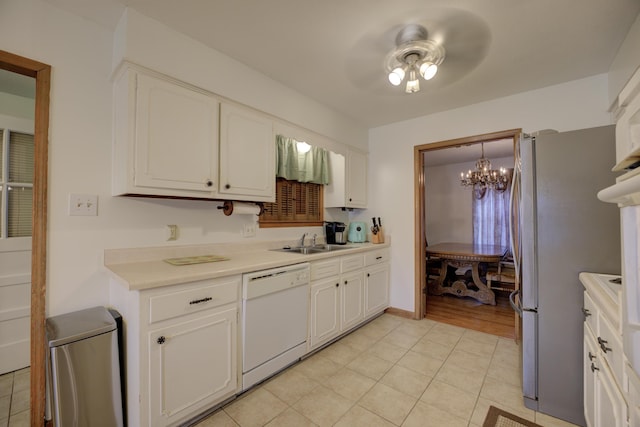 kitchen with light tile patterned floors, sink, stainless steel refrigerator, dishwasher, and white cabinets