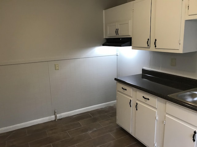 kitchen featuring white cabinetry, sink, and tile walls