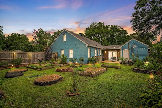 back house at dusk with a yard and a patio